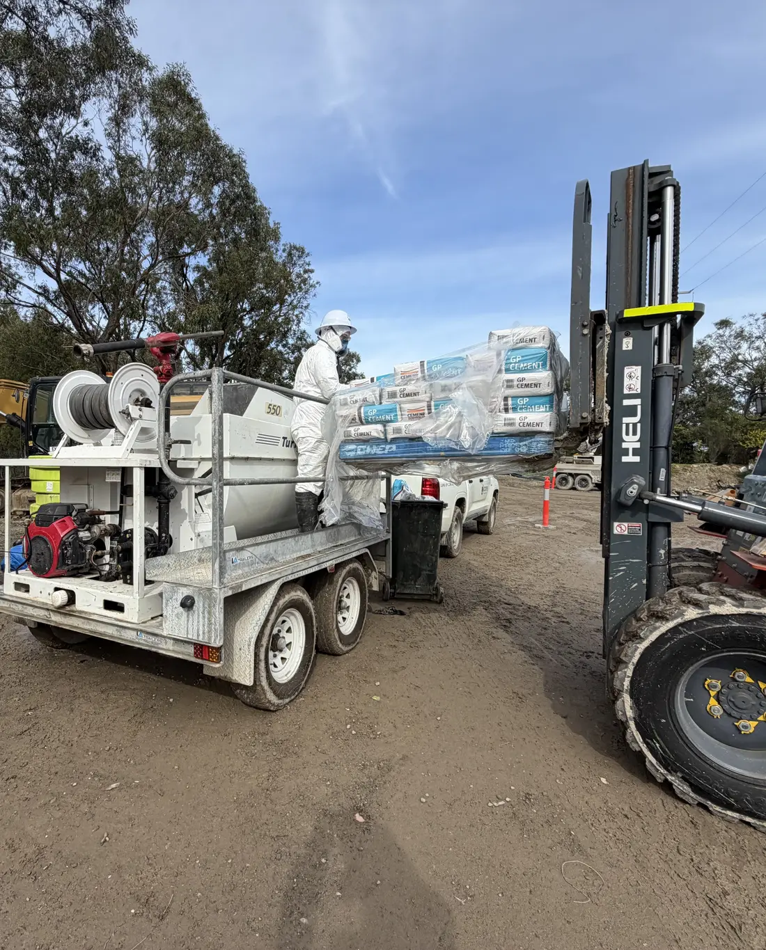 Core Environmental Projects crew loading bagged material into the trailer-mounted Posi-Shell applicator with a forklift