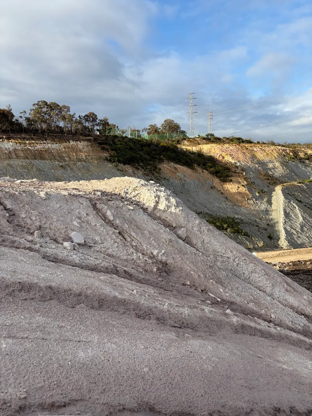Close-up of cured Posi-Shell forming a hard, stucco-like crust on a landfill face